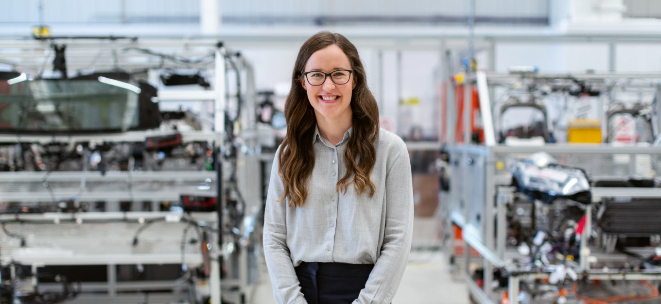 A woman wearing glasses and a grey shirt smiling at the camera