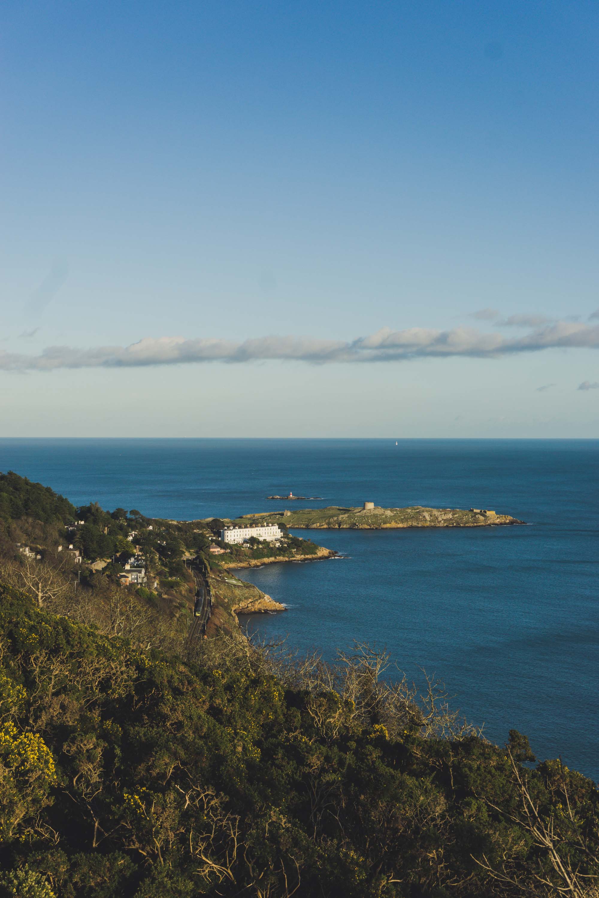Coastal landscape with a train track, some houses and a small island in the sea