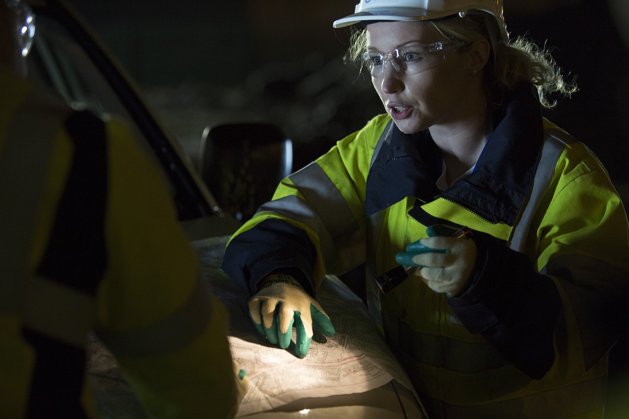 Engineer using a torch to look at a diagram at night