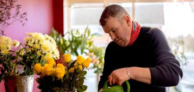 A florist watering a vase with flowers inside a shop