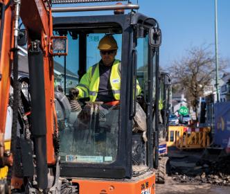 An Uisce Éireann worker in a digger on a roadworks site