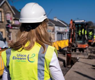 An Uisce Éireann worker on a site with a digger