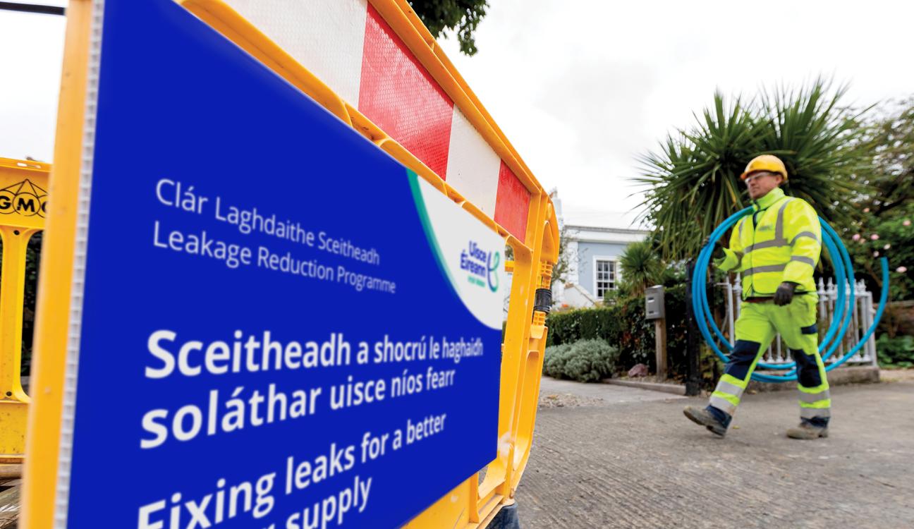 An Uisce Éireann worker carrying blue piping on a site